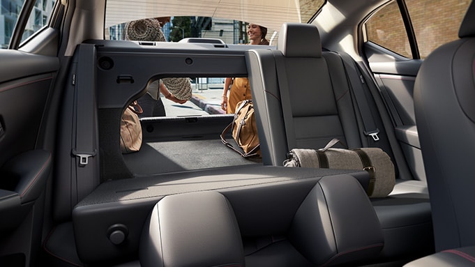 2024 Nissan Sentra displaying people putting a rug into the cargo space with one of the 60/40 split rear seats up and one down.